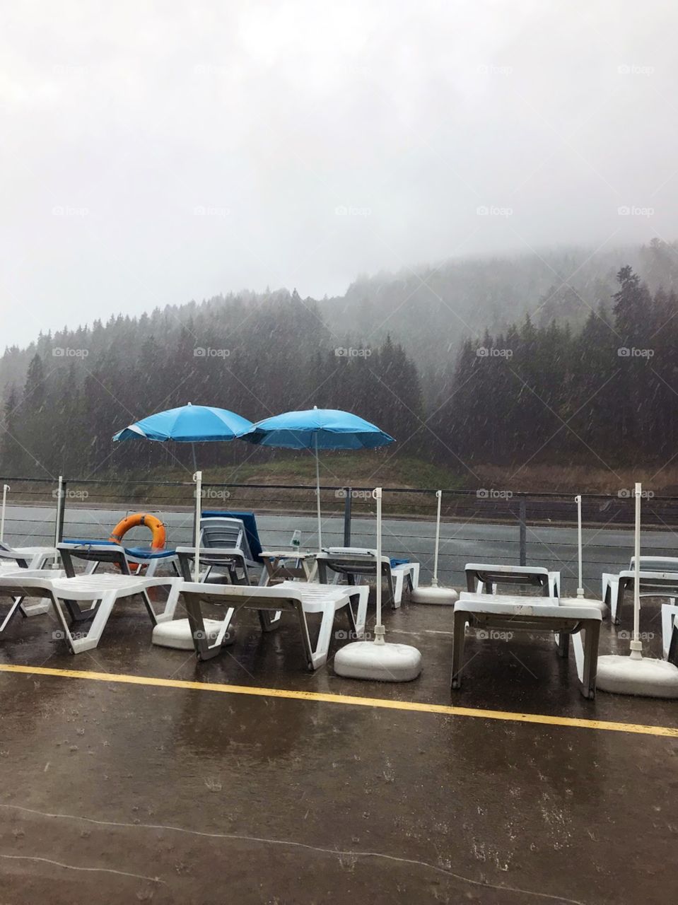 Pair of blue umbrellas on the beach of the mountain lake in rainy weather, Carpathian Mountains 