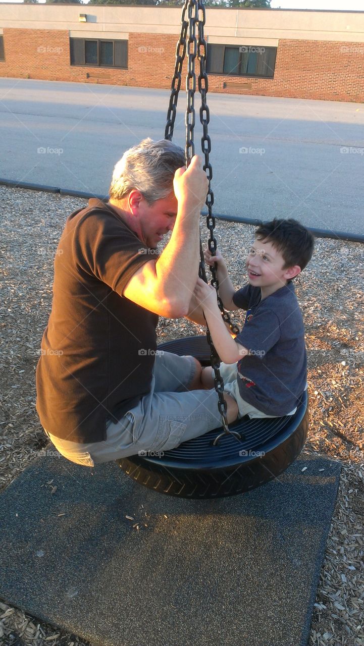 Grandfather and grandson swimming on tire wheel