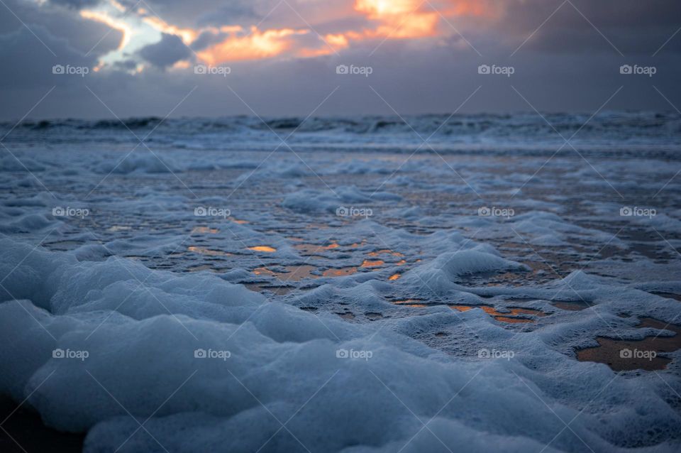 Foam on the beach during sunset
