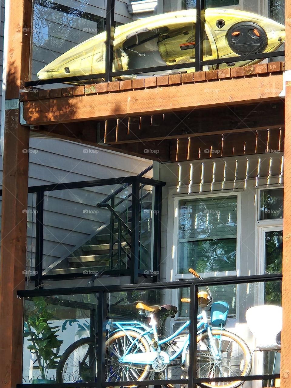 bright sunlight reflecting on glass and wood apartment decks showcasing  bicycle and kayak for Summer adventures