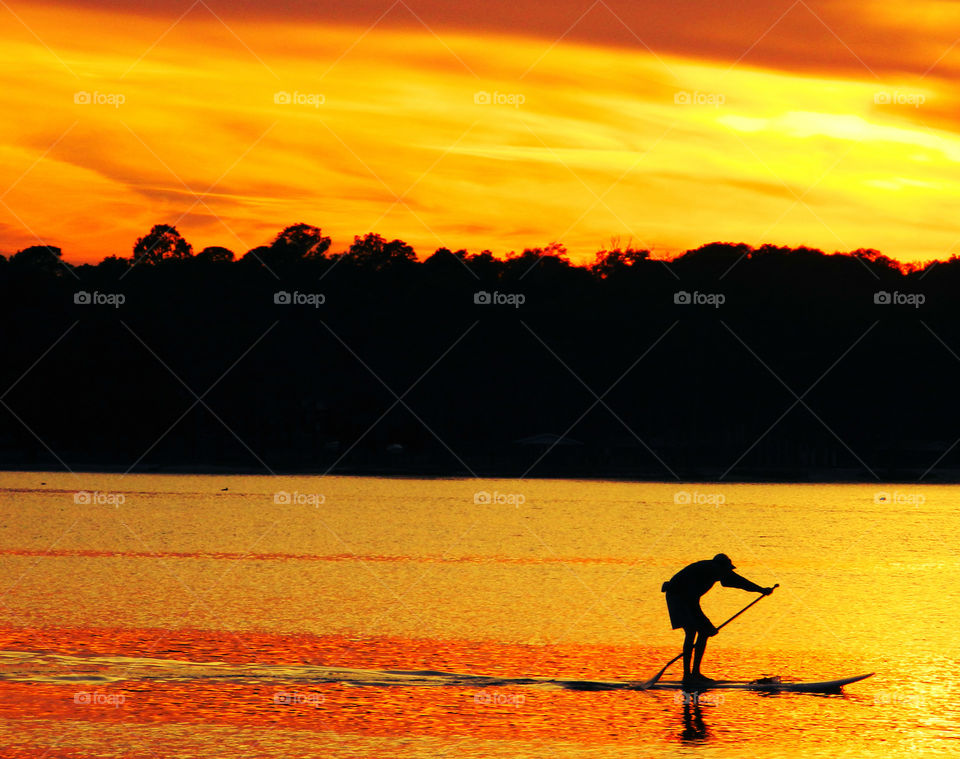 Person rowing at sunset