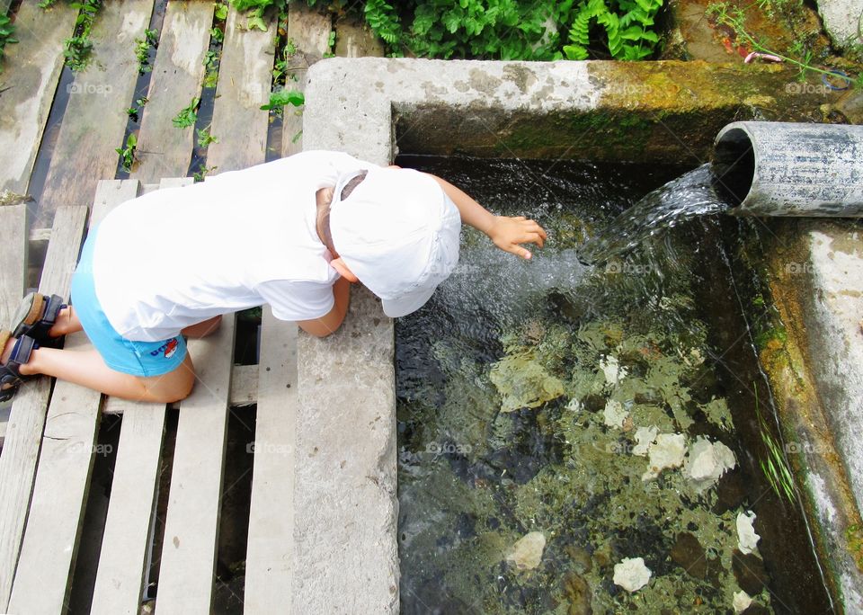 A kid playing on an old spring fountain