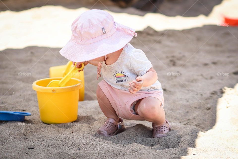 Cute little toddler is playing in the sand