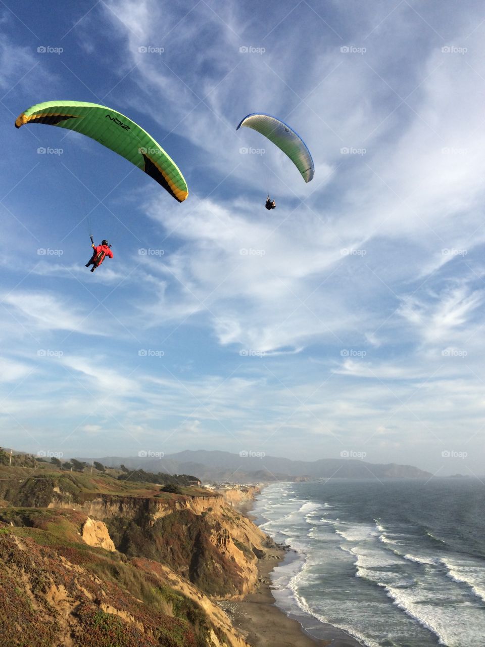 Paragliders at the coast. Two flyers enjoying a hang over the Pacific Ocean. 