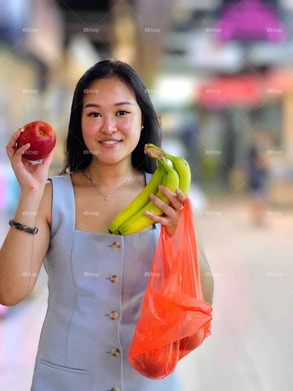 Lady happy having bought her apple and banana from a traditional fruits stall