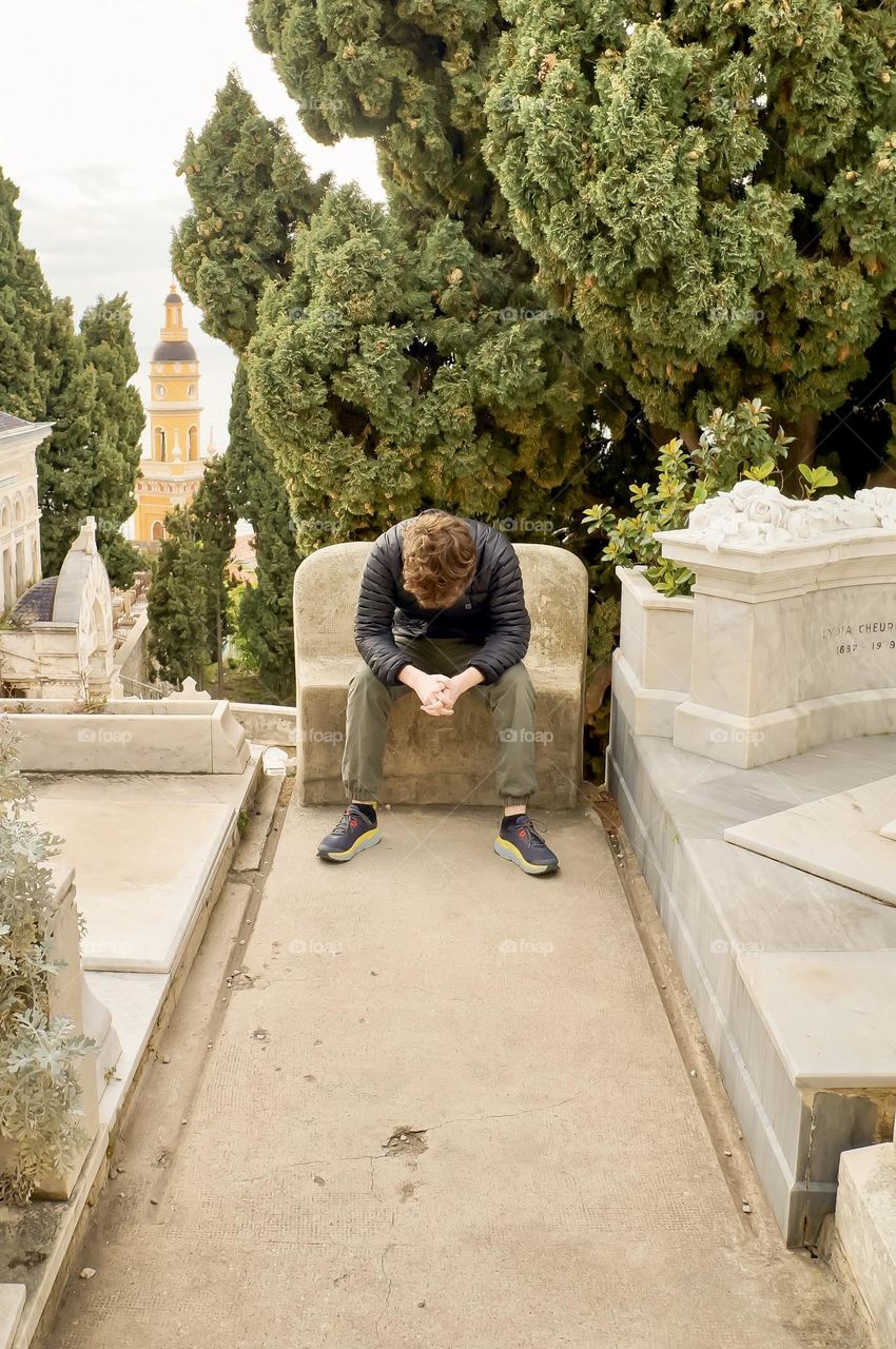 A young man takes a moment at the Cemetery of the Old Château in Menton France, for those who have passed.