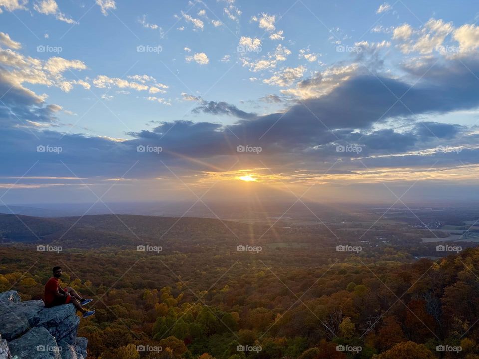 The sun shining between the clouds at a mountain overlook 