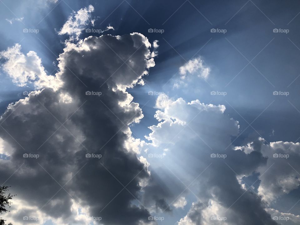 A fantastically gorgeous sky with light emanating behind a dark shaped cloud that proves the photo to be pleasing to the eye. 