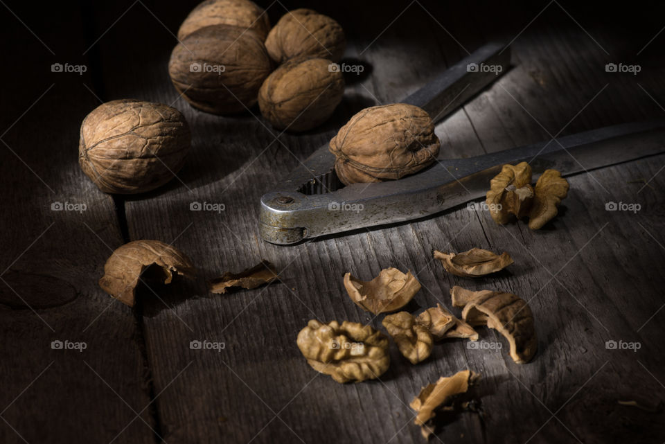 Walnuts and nutcracker on old wooden table, light brush still life