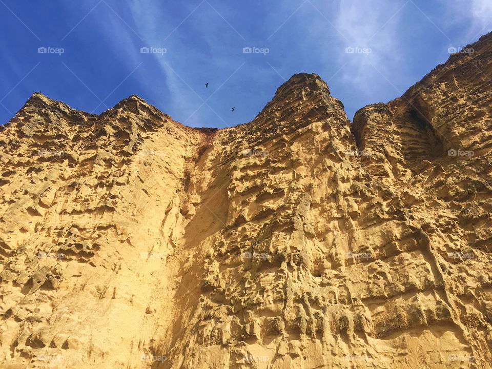 A yellow sandstone cliff face with blue skies.