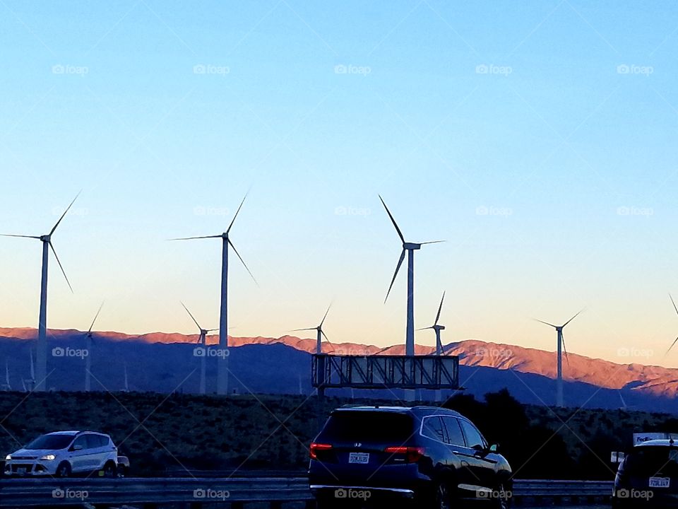 Wind turbines next to a highway full of cars