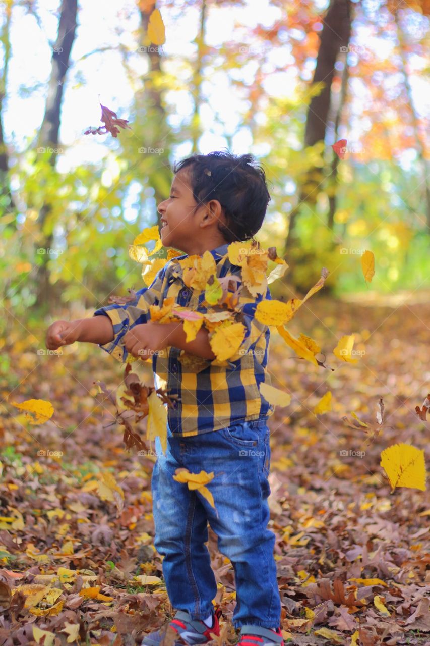 Toddler playing with the leaves in fall season 