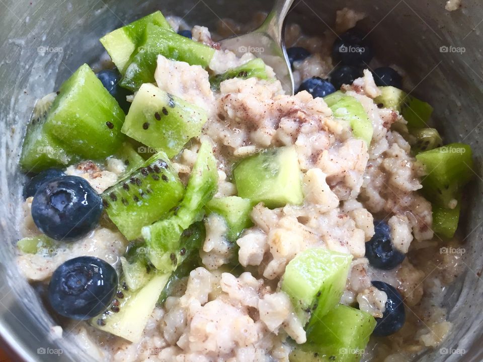 Bluest blueberries and kiwi fruit in homemade oatmeal