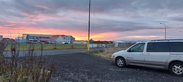 sunset in small town. beautiful red colours highlighting the local school. Family car watching the view.