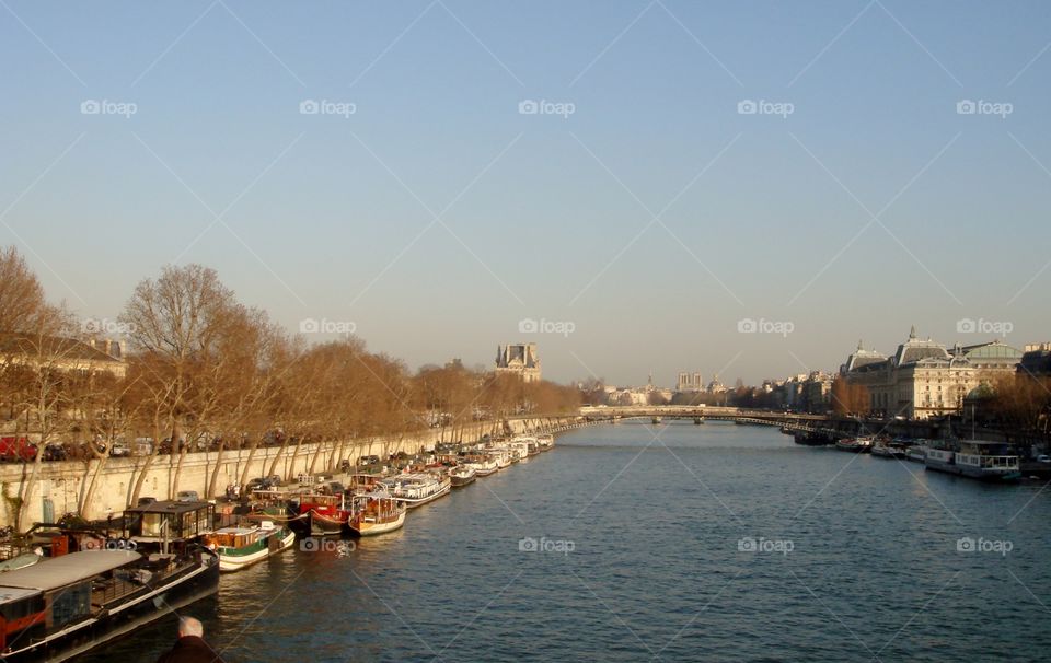 a sunset of the Seine river full of boats in the river bank