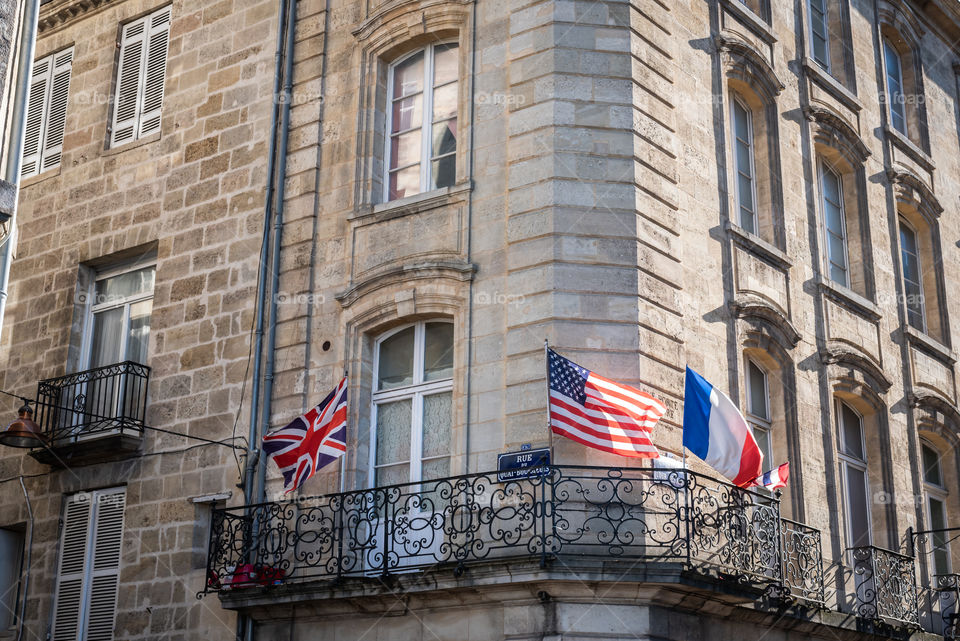 British, American and French flag on a balcony of a building of Bordeaux 