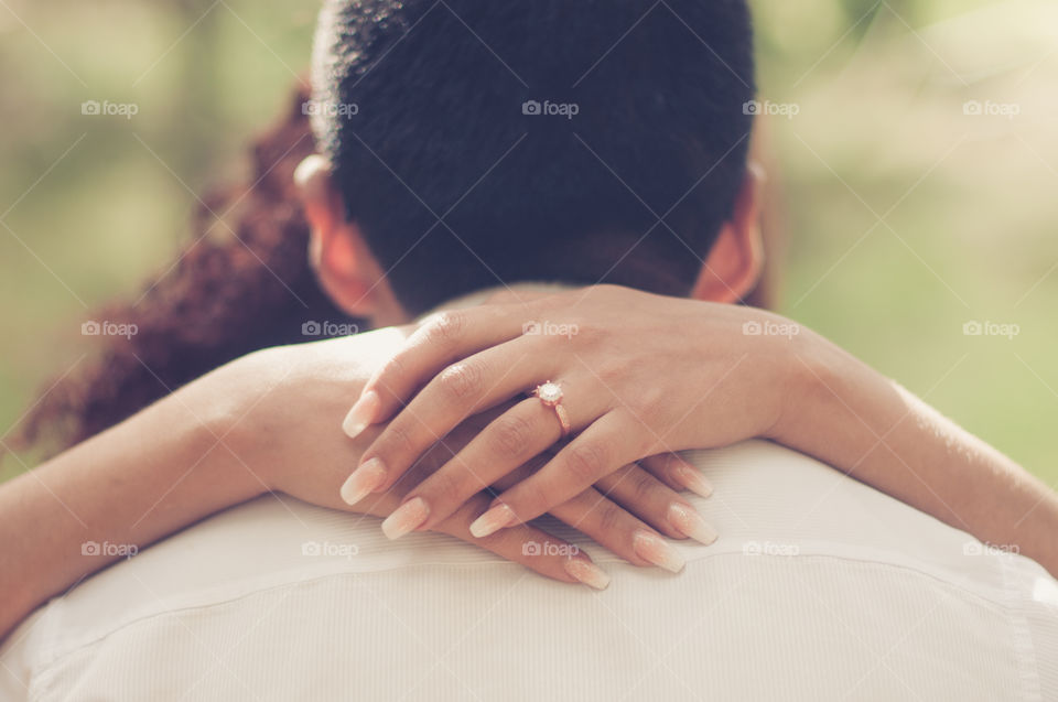 Engagement ring hands crossed around grooms neck