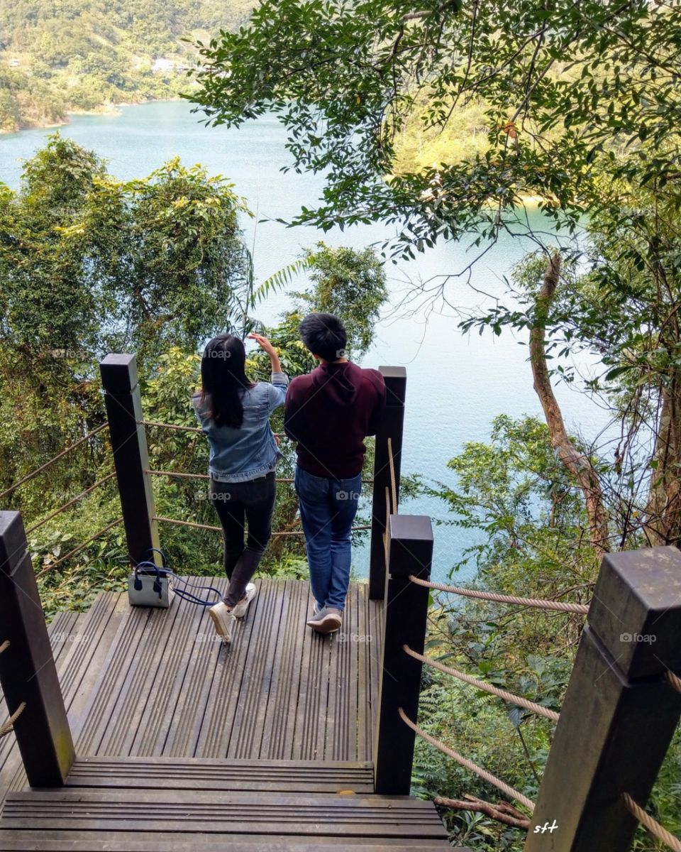 A couple walked at forest trail in holiday, and stood by the lake to watch landscape.they were so lovely!