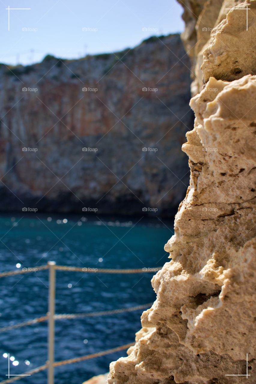 Refined rock by the Mediterranean Sea, with a blurry background.