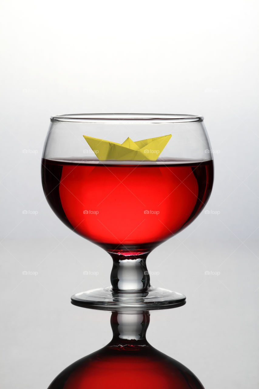 Red wine glass with a origami paper boat