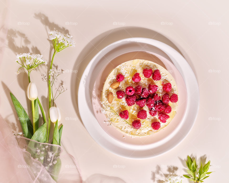 Food composition with raspberry almond cake with and spring bouquet with tulips on a pink background. Sweet pastries with almond flour are gluten-free, low in carb. Keto diet. Healthy dessert