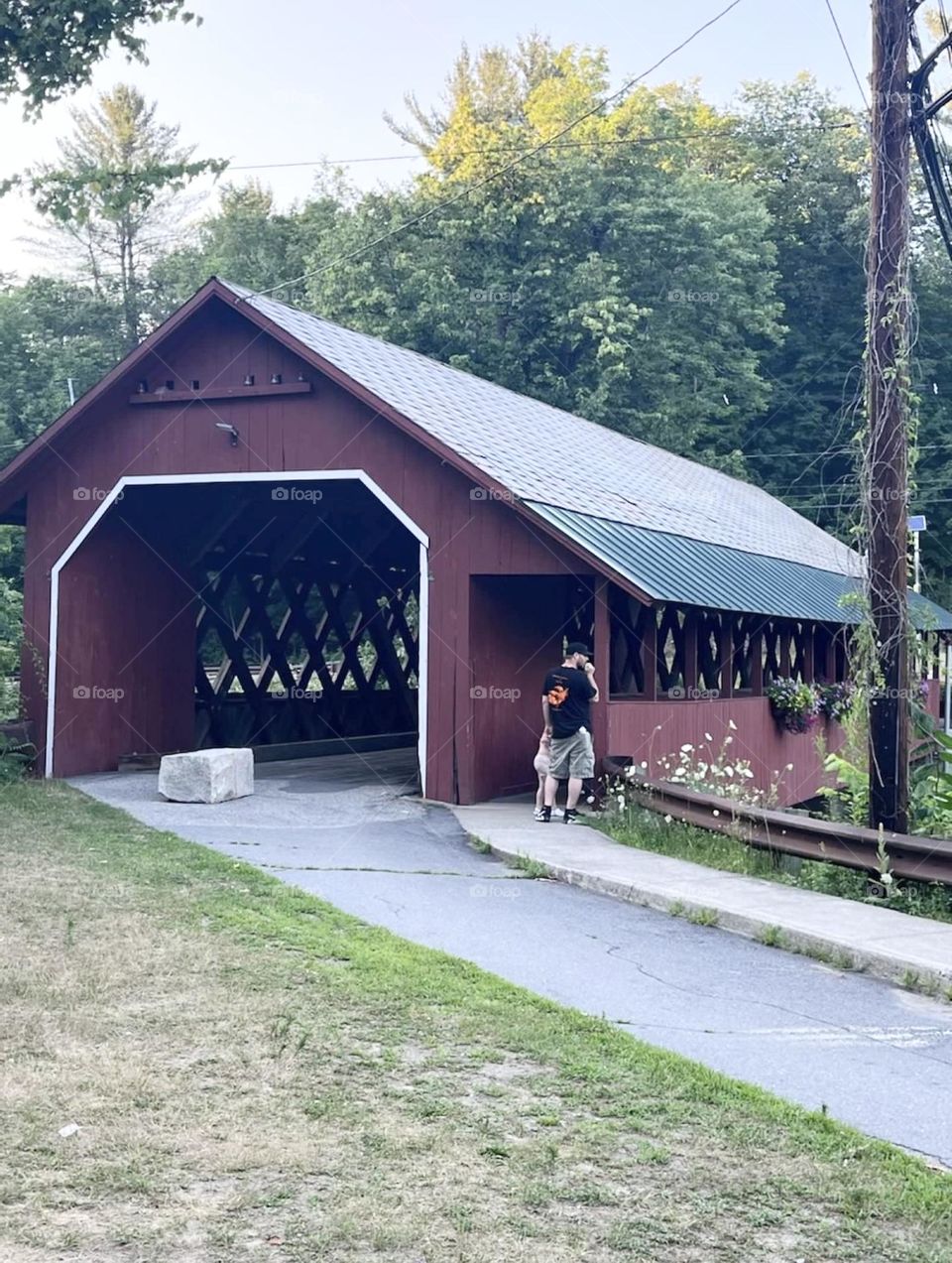 A red covered bridge on the countryside roads of northeastern United States on a sunny summer afternoon. 