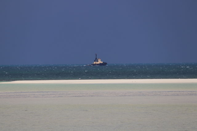Tugboat on the ocean horizon in storm at low tide minimalist 