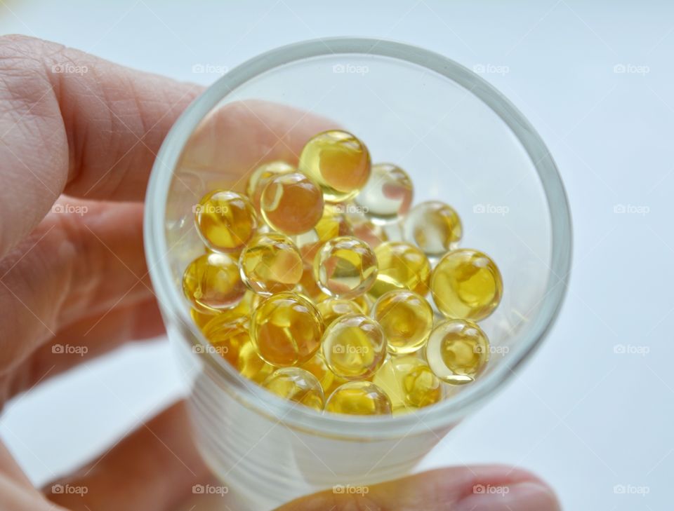 vitamins capsules in glass cup in hand on a white background, medical