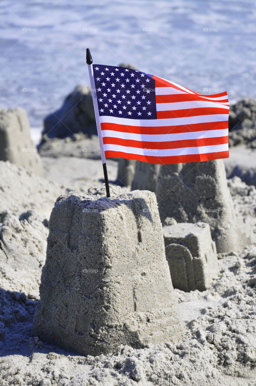 Sandcastle with an American flag crowning it. 