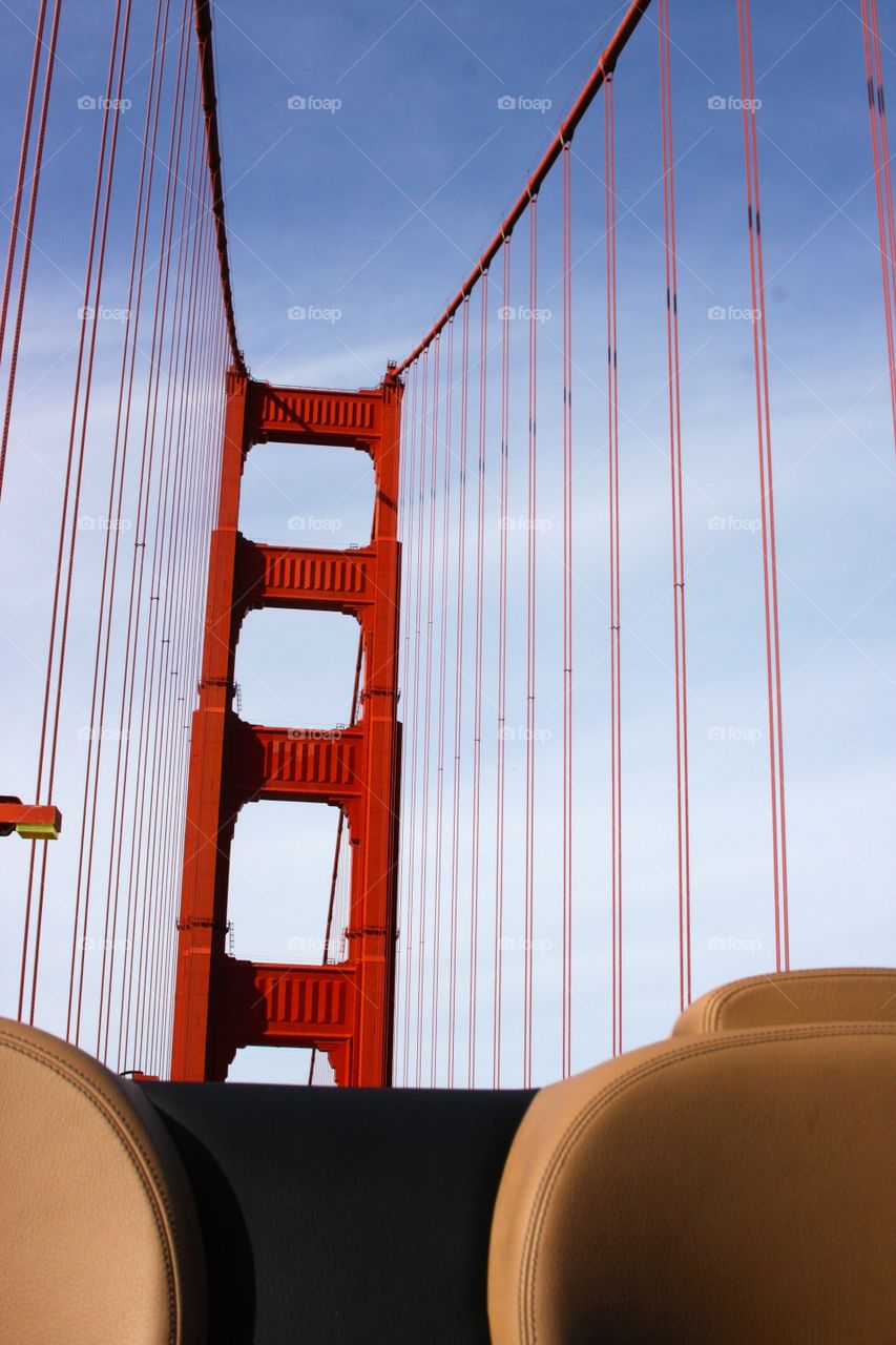 A convertible with the top down going across the Golden Gate Bridge. 