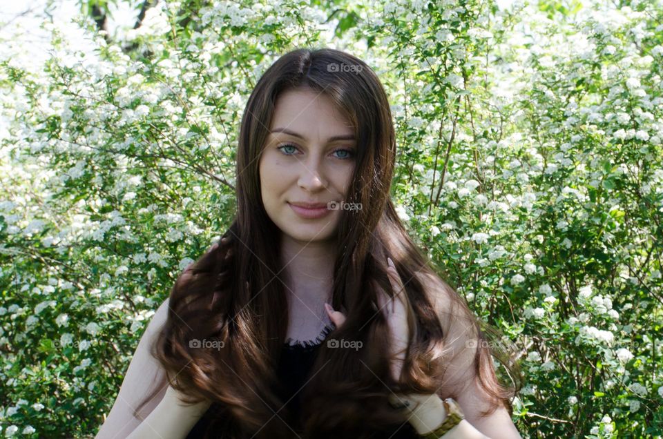 Beautiful Young Girl on Background of Flowers