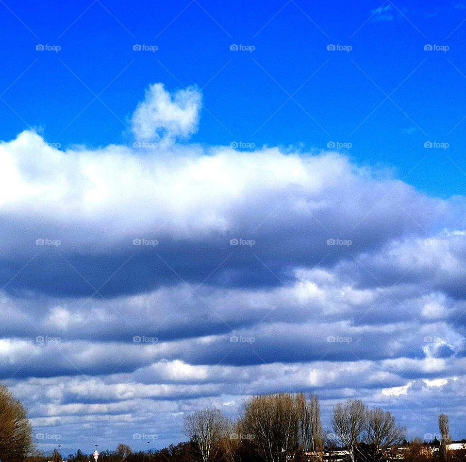 Clouds.  There is a blue sky in the sky.  The sky begins to cover low dark clouds.  A cloud in the form of the letter "N" is visible above one cloud.  Surprises of nature