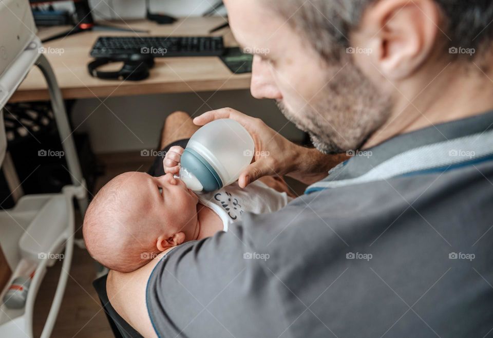 Father feeding baby son with bottle of baby formula