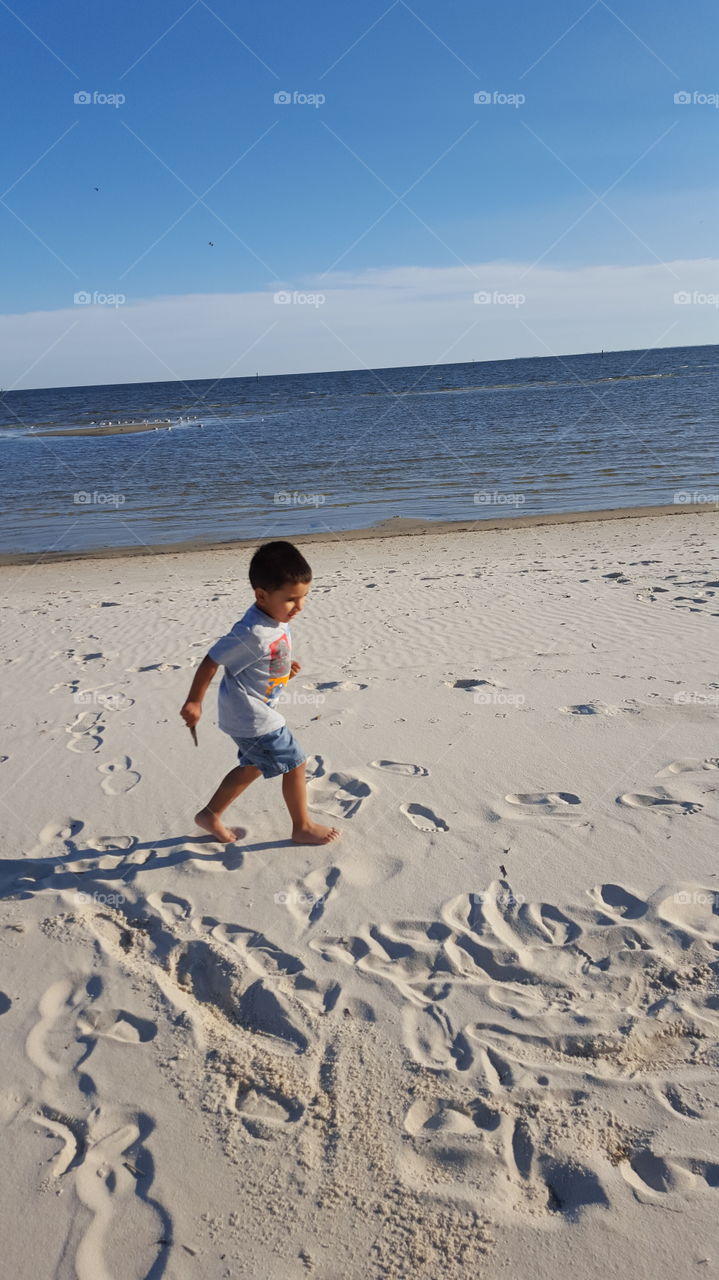 Boy walking on sandy beach