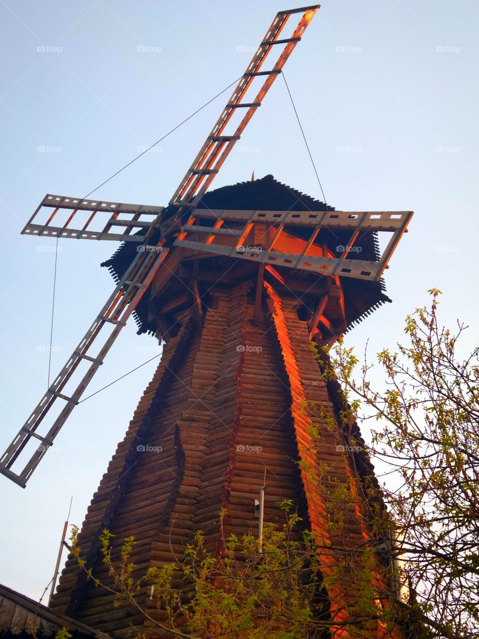 A wooden mill on which the orange rays of the setting sun fall.  Sunset in the city