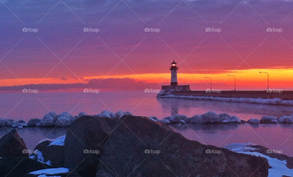 Lighthouse near sea against dramatic sky