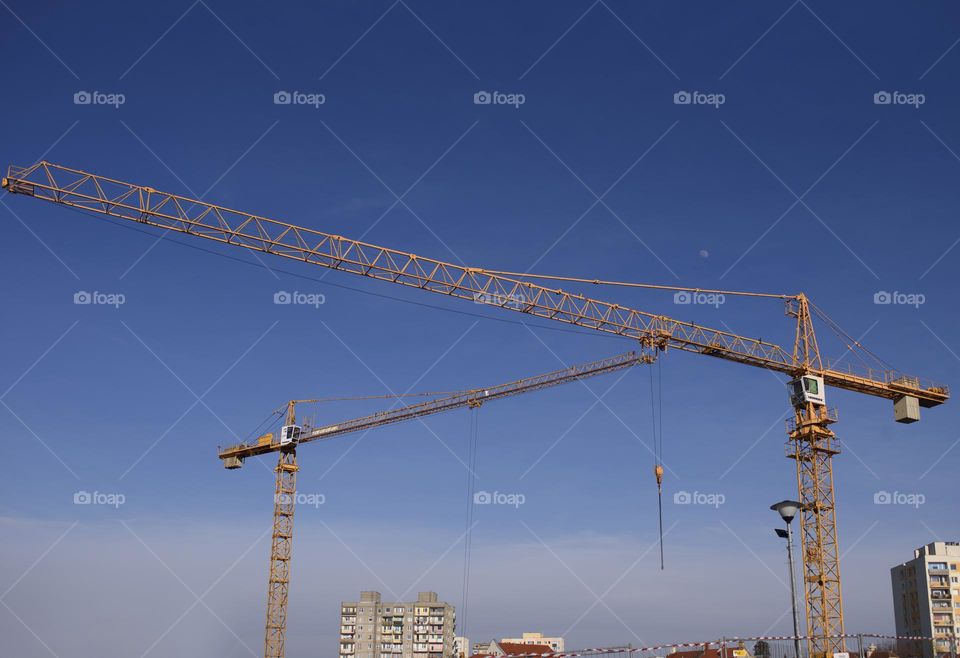 Poland, Zielona Góra, 04.12.2022. Arrows of construction cranes against the blue sky