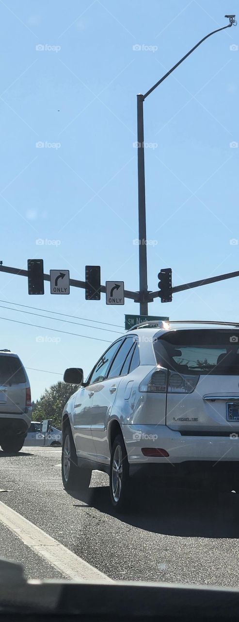 silver car waiting at a red light in Oregon commuter traffic on a clear blue sky day