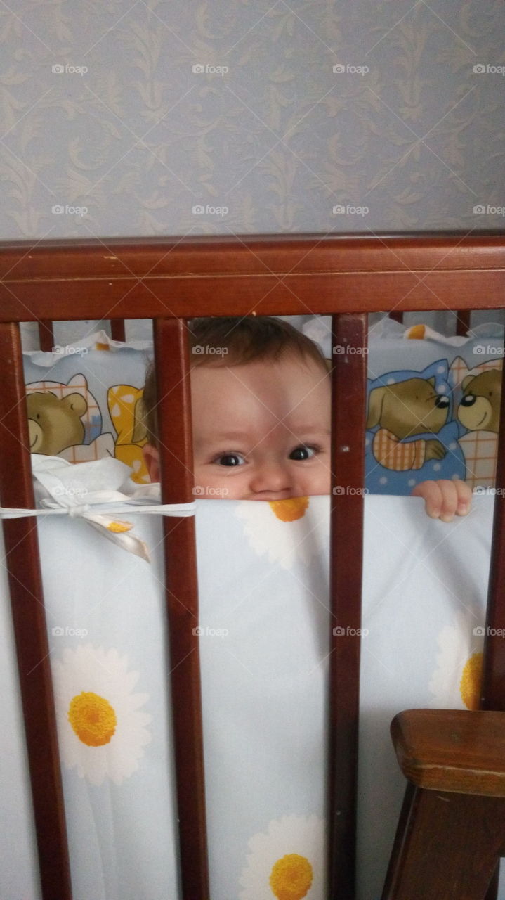Little kid peeking from the cradle