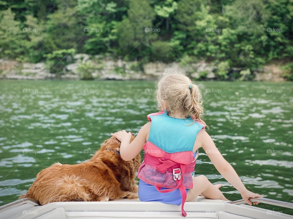 Just a kid and her dog on a boat on a beautiful summer day 