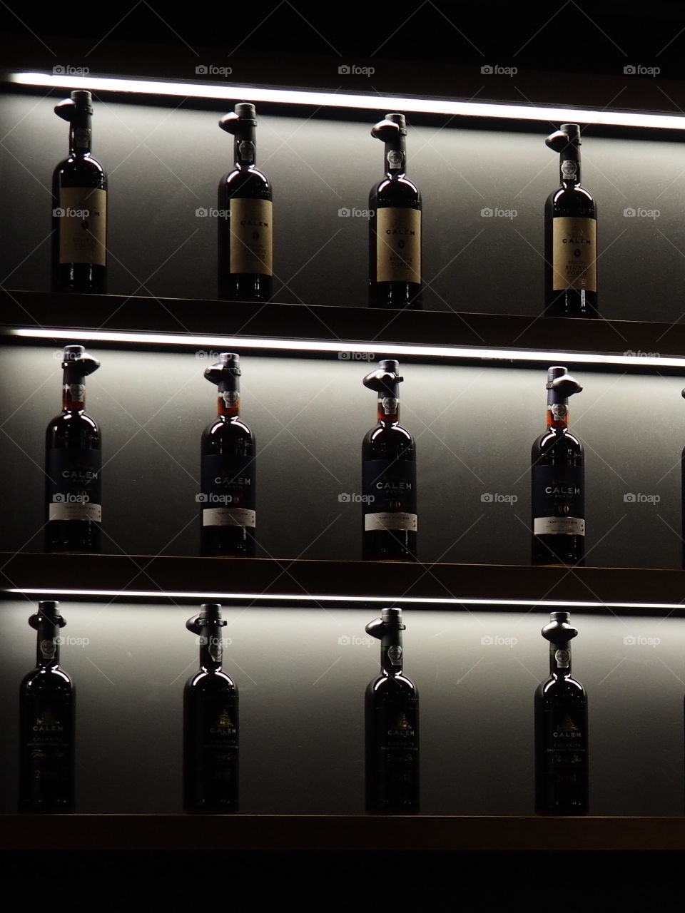 Bottles of Port wine in a showroom in Porto, Portugal in front of dark lightning.