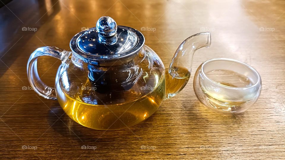 Transparent teapot and a glass on the table.