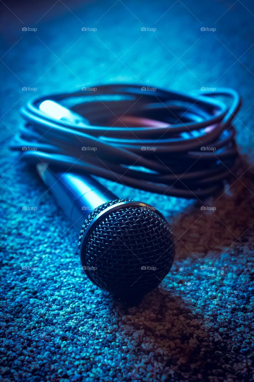 A curled up vocals microphone on blue carpet with blue lighting and highlights 2022.