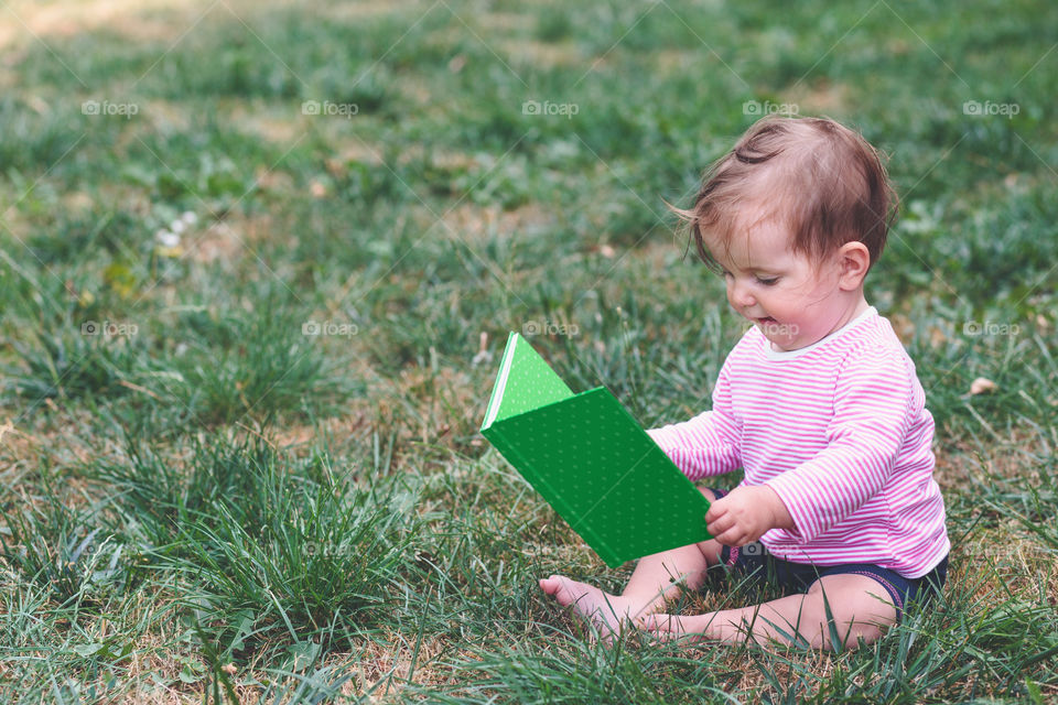 Cute baby in park with book in hand