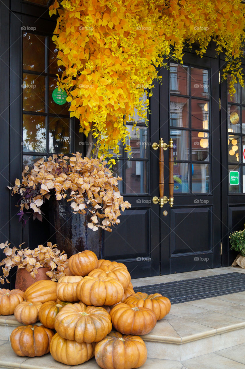 Autumn composition in front of doors, pumpkins, yellow and dry brown leaves