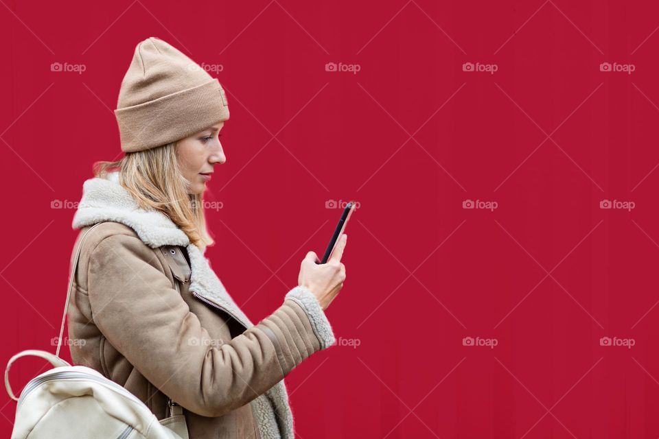 Woman using mobile phone near trendy 2023 year background color viva magenta 