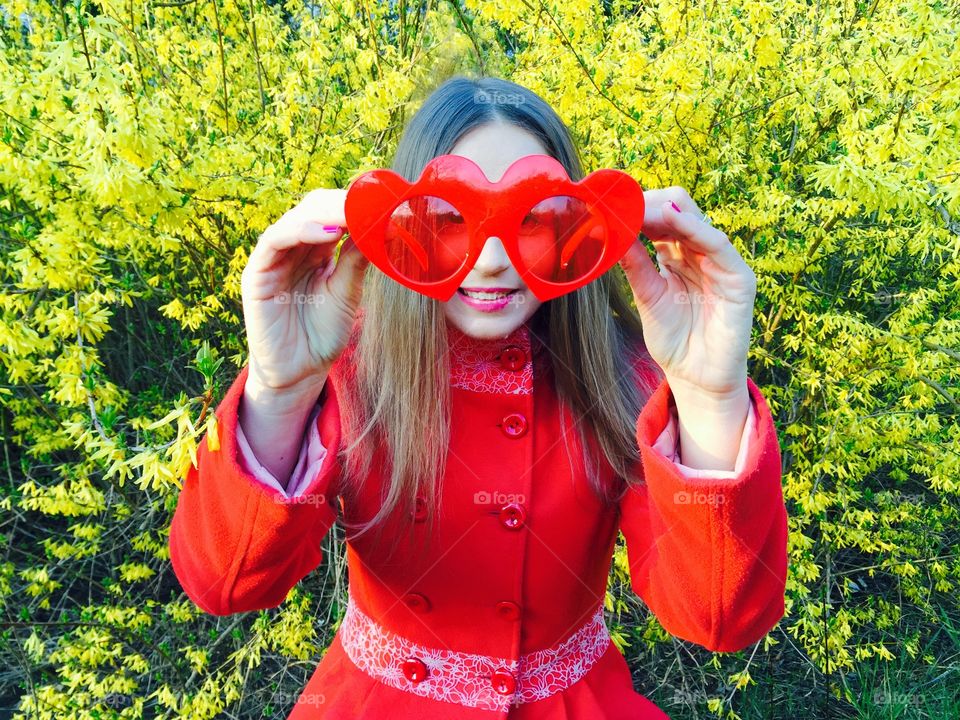 Woman holding red heart shape eyeglasses