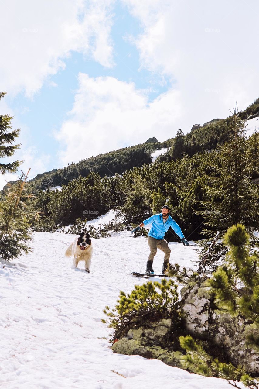 man snowboarding with his dog