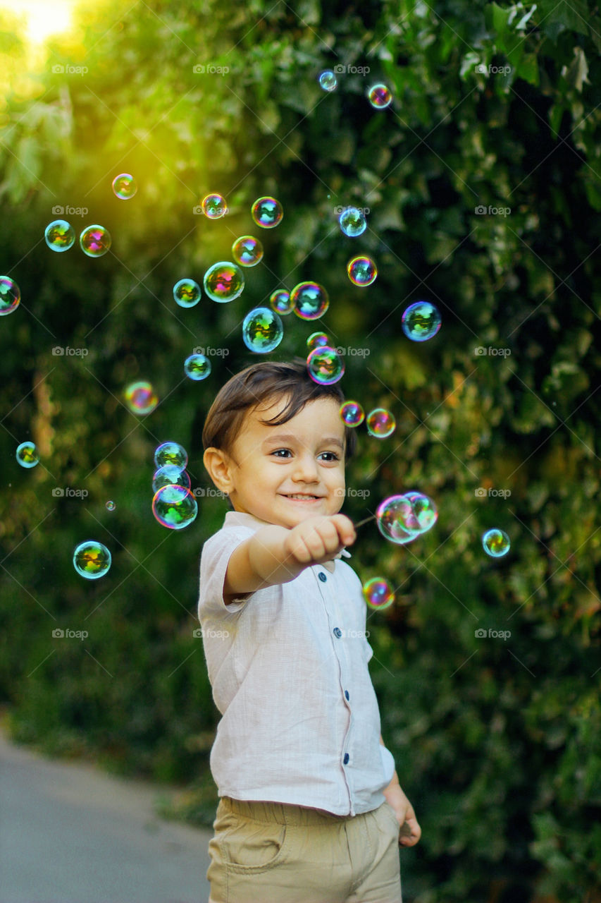 two year old cute smiling boy playing bubble soap sunny day,happy day