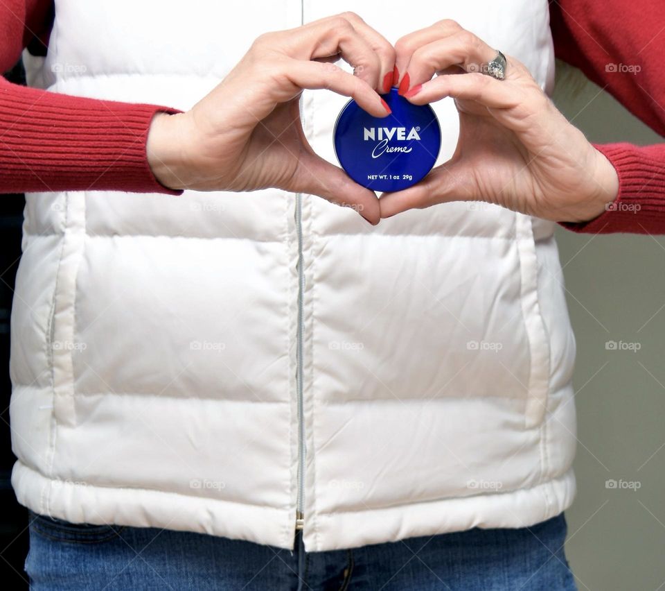 Nivea creme held in hands in the  shape of a heart 